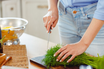 Woman cutting parsley on wooden board in kitchen