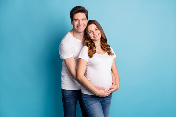 Poster - Photo of young lovely happy positive good mood couple family husband hug pregnant wife isolated on blue color background