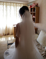 Wall Mural - the bride in a white dress with a veil stands in her room