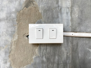 Old and dirty light switch on the polish concrete wall background. Example of a bad switch, a bad job. It can be used in billboards for electrical equipment stores