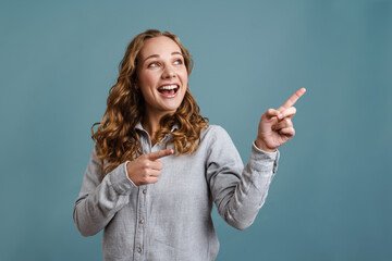 Excited beautiful blonde girl smiling and pointing fingers aside