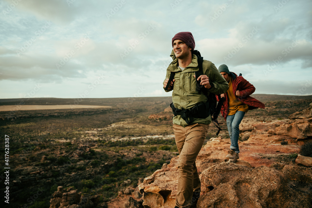 Caucasian male hiking holding backpack walking through mountain ...