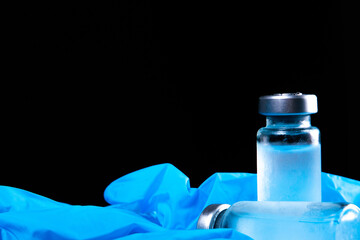 2 doses of Sars-Kov-2 coronavirus vaccine in transparent glass ampoules, covered with frost, on a dark background, short focus, toning