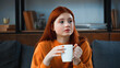 © LIGHTFIELD STUDIOS - Red haired girl with cup looking away at home