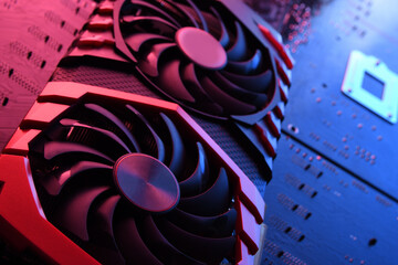 Computer game graphics card, videocard with two coolers on circuit board ,motherboard background. Close-up. With red-blue lighting