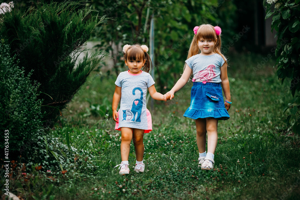 Beautiful young girls in a long dress and a skirt are walking in the ...