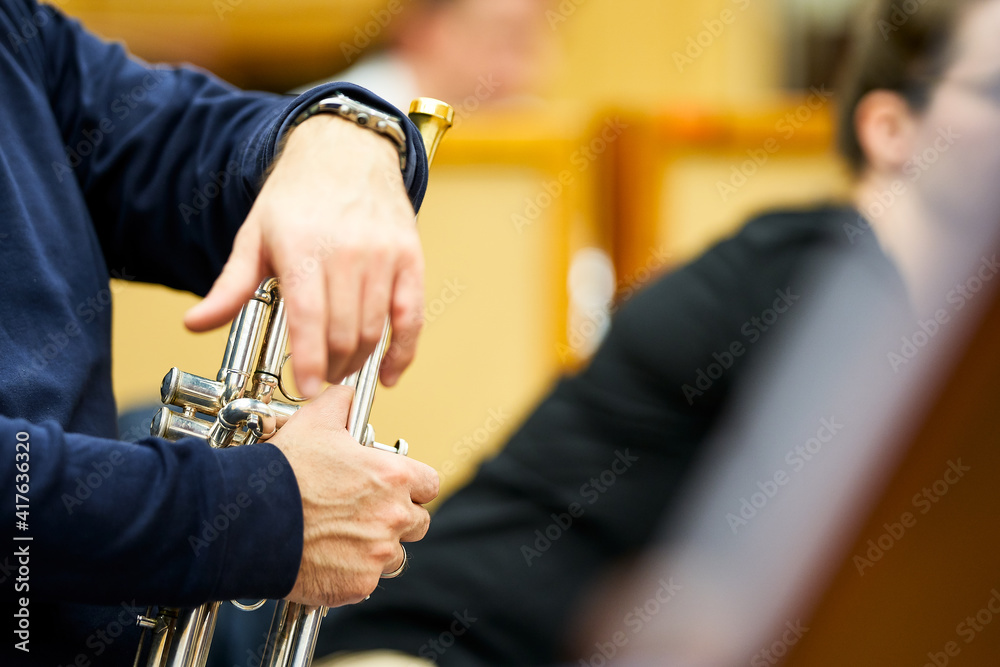 Trumpeter's hands resting on the trumpet during a break in the rehearsal. - obrazy, fototapety, plakaty 