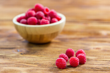 Heap of raspberries lying on a wooden board in kitchen prepared to be served. Fresh ripe fruit of pink color from close up with copy space. Concept of healthy diet.