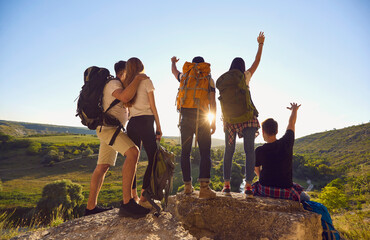 Wall Mural - Young hikers raise their hands while standing on top of the mountain and enjoying nature.