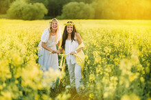 Two Women In A Rapeseed Field With A Bicycle Enjoy A Walk In Nature Rejoicing
