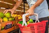 Fototapeta  - Homem segurando cesta de frutas e legumes no mercado.