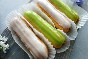 Canvas Print - Vanilla and pistachio eclairs on wooden board on table