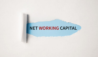 Net Working Capital. text on white paper over torn paper background.