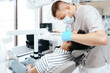 © diignat - Smiling young man sitting in dentist chair while doctor examining his teeth