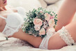 Boudoir wedding morning. Beautiful sexy bride in white underwear with garter belt and bouquet in soft defocus