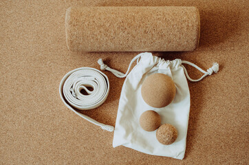 High angle flat lay of props fo self care techniques: myofascial release, yoga therapy, set on a cork mat background. Belt, cork massage balls. Concept: eco friendly, sustainable props.