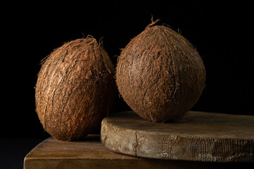 Isolated coconut on a black background. Two whole coconuts on a dark background. Healthy fruit