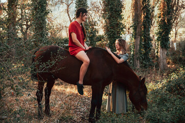 Wall Mural - Two women friends chatting and taking a ride with their horse through the countryside