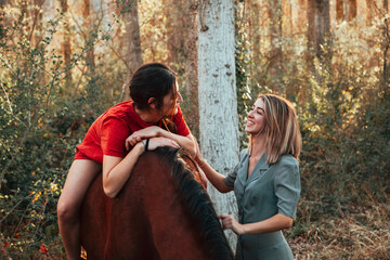 Wall Mural - Two women friends chatting and taking a ride with their horse through the countryside