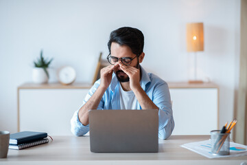 Wall Mural - Eyes Fatigue. Arab Freelancer Man Tired After Working Remotely On Laptop Computer