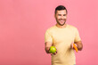 © denis_vermenko - Diet concept. Portrait of man isolated on a pink background holding carrot and apple. Vegetarian preparing a meal. Smiling guy loves fruits and vegetables.
