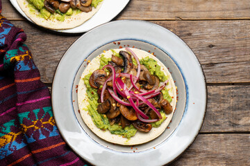 Mushroom and guacamole tacos on wooden background. Mexican food