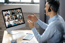 Virtuak Business Meeting Online. Successful Businessman Is Negotiating With Multiracial Business Partners On A Video Conference Using A Computer While Sitting At His Workplace