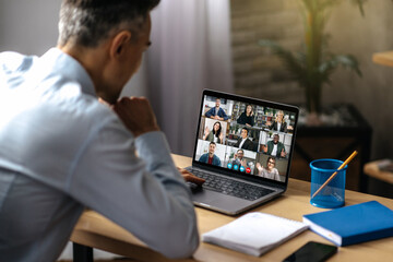 Wall Mural - Online video communication. A successful adult businessman uses a laptop for video conference with business partners. A manager or ceo is sitting at his desk, talking on a video call with colleagues