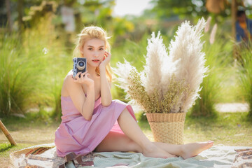 young pretty woman holding camera and sitting relax in public park.