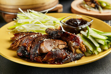 Wall Mural - Peking duck chinese food. Yellow plate with vegetables and sauce on dark slate table. Chinese, asian, authentic food concept