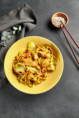 Canvas Print - Curry Udon Noodles. Asian curry udon in yellow plate with wooden chopstick on dark slate table. Asian, authentic food concept