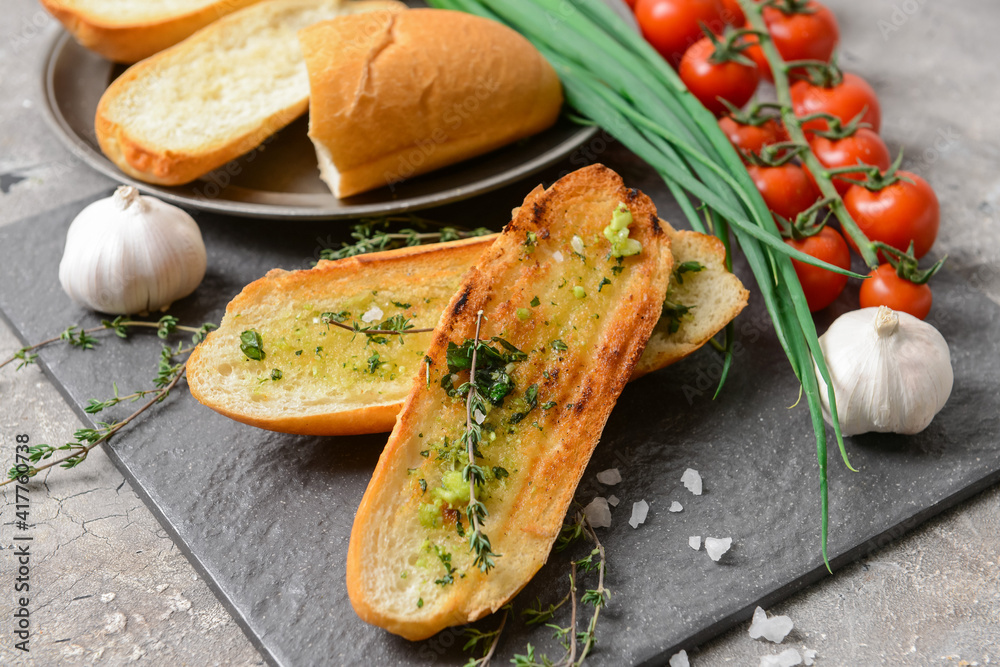 Toasted bread with garlic and vegetables on grey background