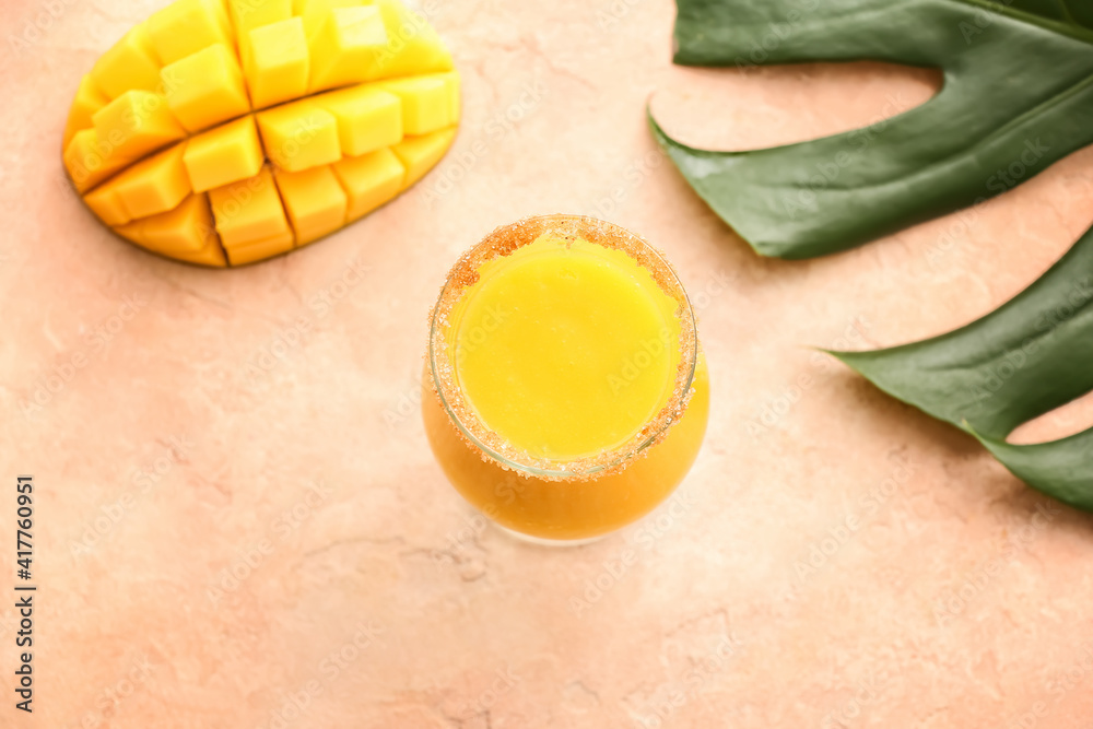 Glass of tasty mango smoothie on color background
