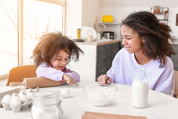 Cute African-American sisters cooking in kitchen