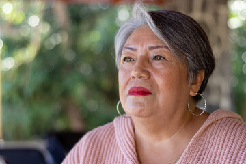 older adult with gray hair, pink blouse, unfocused background