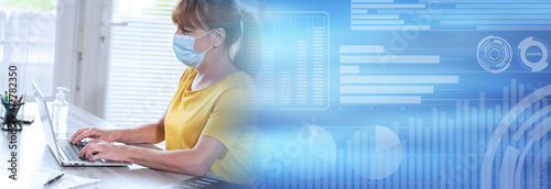 Photo Businesswoman with medical face mask and working on laptop from home; panoramic