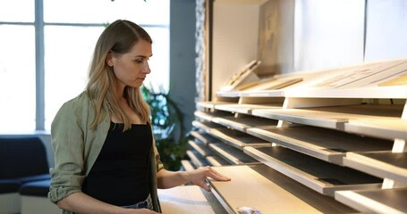 Wall Mural - young woman choosing materials from samples for her new home at interior design store