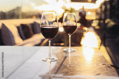 Two glasses of red wine on a rooftop bar terrace with a city view