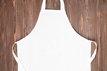 Wall Mural - Blank white apron template on wooden background, copy space. Kitchen, cooking clothing mockup