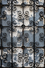Wrought Iron Fence Or Gate On A Weathered Blue Wall With Cracked White Paint. Portrait Orientation.