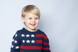 © studiomay - Smiling kid in sweater with USA American flag on white background with copy space