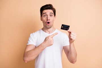 Sticker - Portrait of impressed brunet man point card wear white t-shirt isolated on beige color background