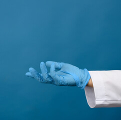 Wall Mural - female hand in blue latex gloves on a blue background