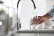 © New Africa - Man pouring water into glass in kitchen, closeup