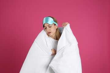 Sticker - Young woman in sleeping mask wrapped with soft blanket on pink background