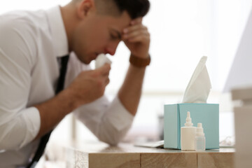 Sticker - Ill businessman in office, focus on table with box of paper tissues, nasal spray and drops