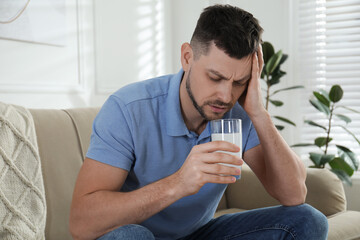 Wall Mural - Man taking medicine for hangover at home