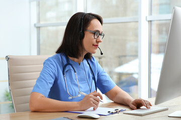 Wall Mural - Doctor with headset and computer consulting patient online in office. Hotline service