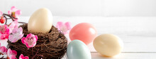 Close Up Of Colorful Easter Eggs In The Nest With Pink Plum Flower.