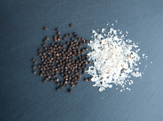 Black pepper, Piper nigrum,  peppercorn and fleur de sel salt, Flake salt  on stone grey background